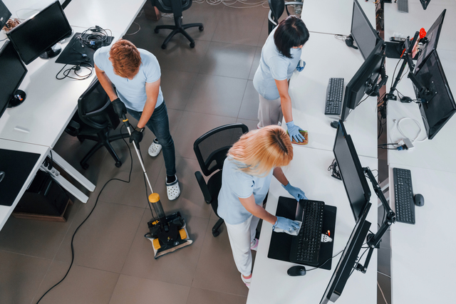 Top view. Group of workers clean modern office together at daytime.